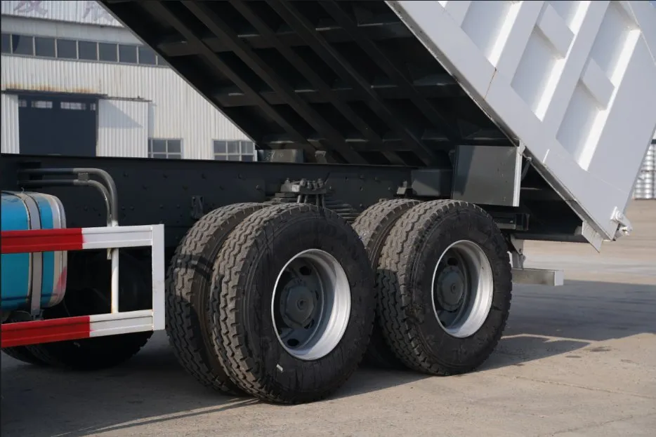 Hydraulic dump body elevated on Sinotruk HOWO 6x4 tipper truck showing subframe crossmembers and tandem drive axles