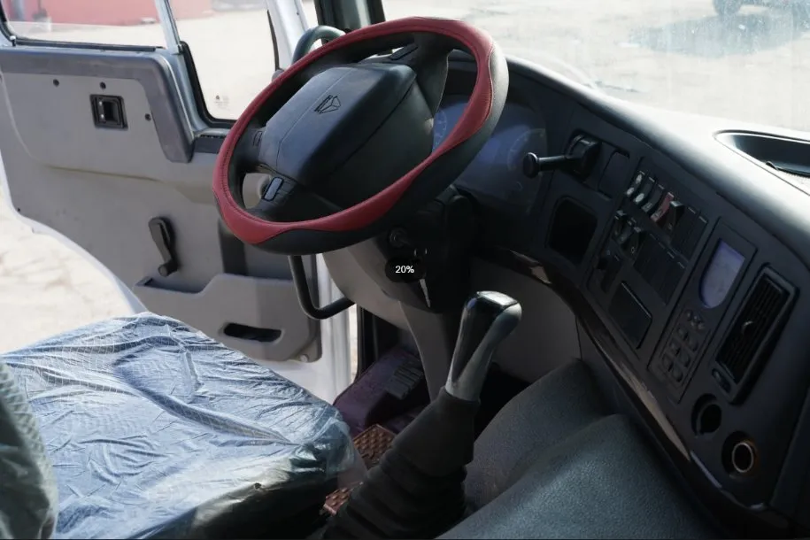 Refurbished HOWO driver cabin interior showing steering wheel, manual transmission gear shifter, and dashboard controls