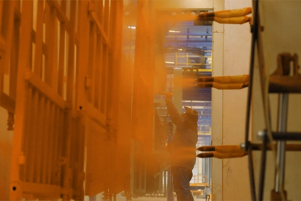 Automated electrostatic powder coating applied to Kales flatbed semi-trailer components after e-coat, providing durable, zero-VOC finish on visible parts like side rails and toolboxes.